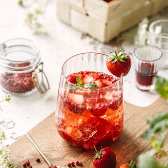Ein erfrischendes Getränk mit frischen Erdbeeren und Minze, serviert in einem eleganten Glas auf einem Holzbrett.