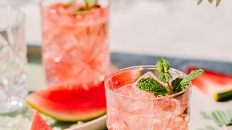 Zwei Gläser mit einem erfrischenden Wassermelonen-Cocktail, garniert mit frischer Minze, auf einem hellen Tisch.