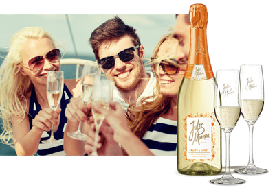 Eine Gruppe von Freunden hebt Gläser mit Sekt an Bord eines Bootes, während sie fröhlich lachen und die Sonne genießen.