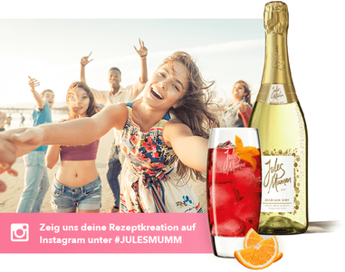 Eine Gruppe junger Menschen feiert am Strand, während eine Frau mit einem Drink in der Hand fröhlich in die Kamera lächelt.