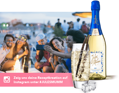 Freunde posieren lachend für ein Foto, umgeben von Getränken und einer festlichen Atmosphäre am Strand bei Sonnenuntergang.