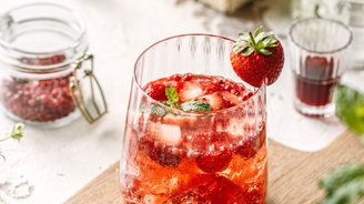 Ein erfrischendes Getränk mit frischen Erdbeeren und Minze, serviert in einem eleganten Glas auf einem Holzbrett.